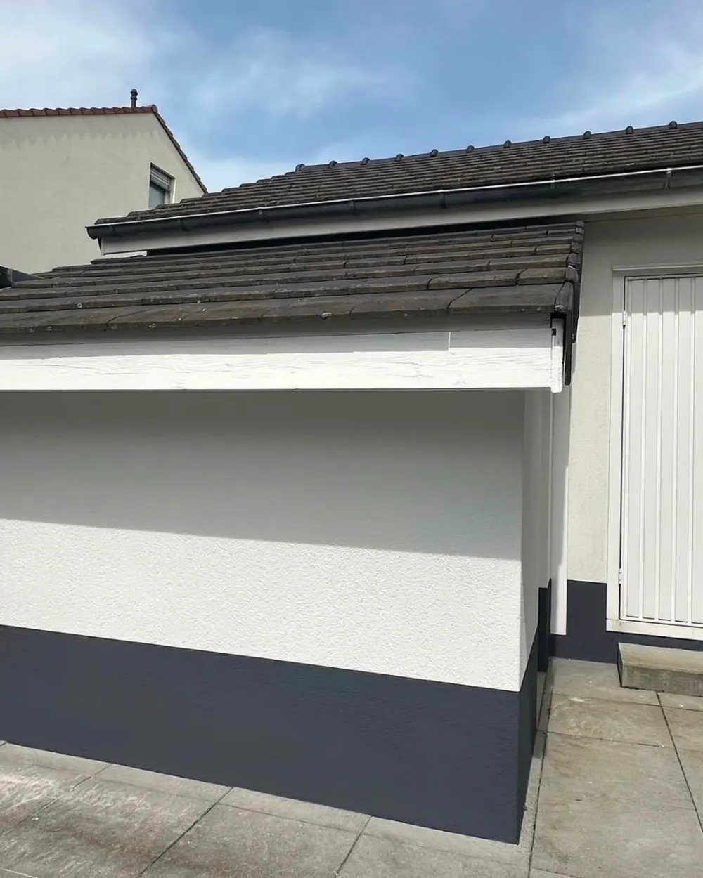Façade de garage après travaux : enduit blanc assaini et soubassement anthracite