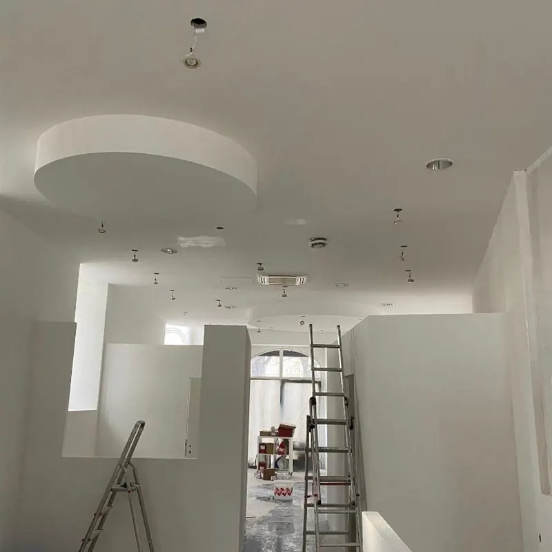 Faux-plafond blanc avec découpe circulaire et spots encastrés, chantier en cours