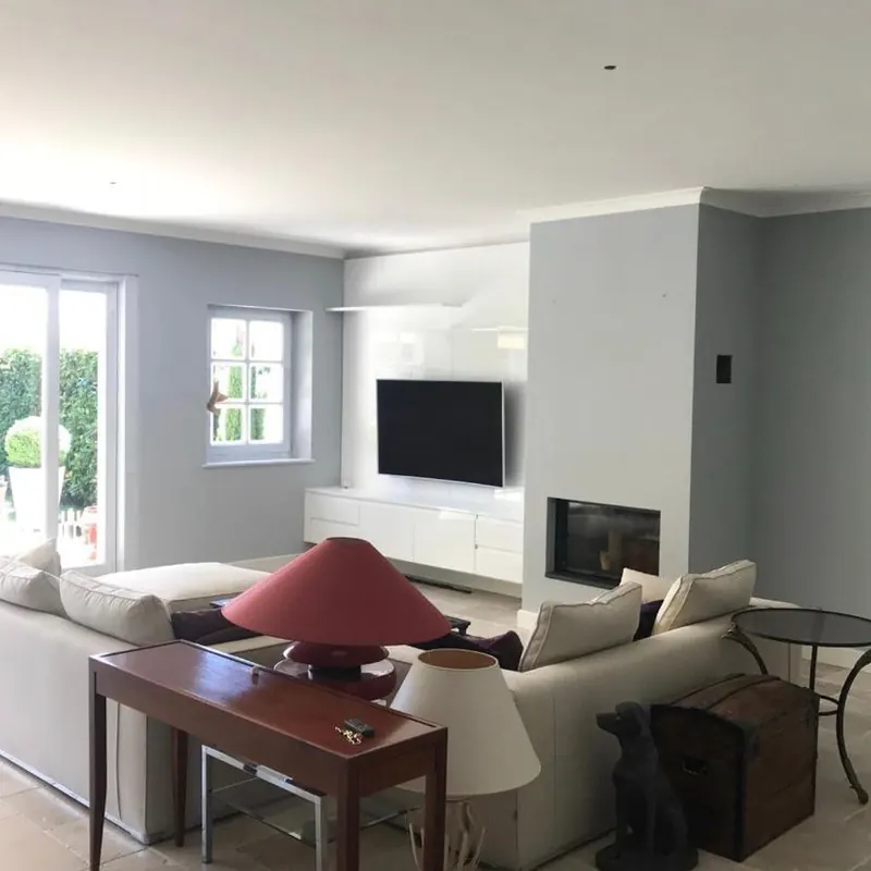Séjour aux murs gris clair avec cheminée et meuble TV intégré